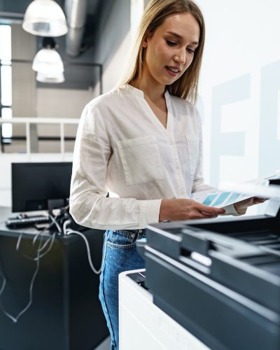 Young employee using modern printer in office Young employee using modern printer in office